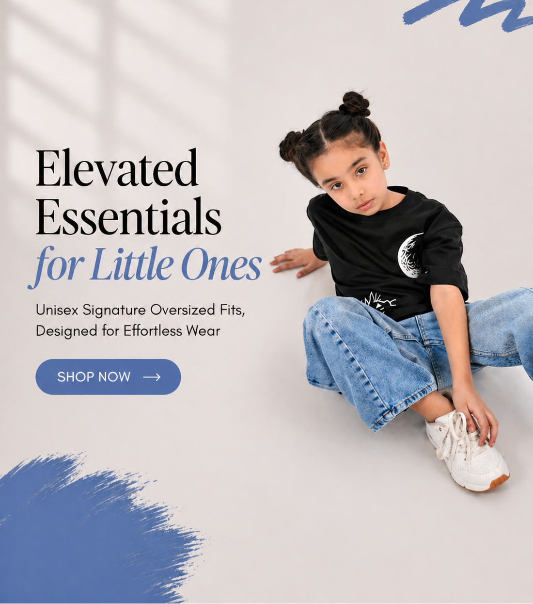 Child wearing a black oversized shirt and blue jeans sitting on a white floor with promotional text and branding.